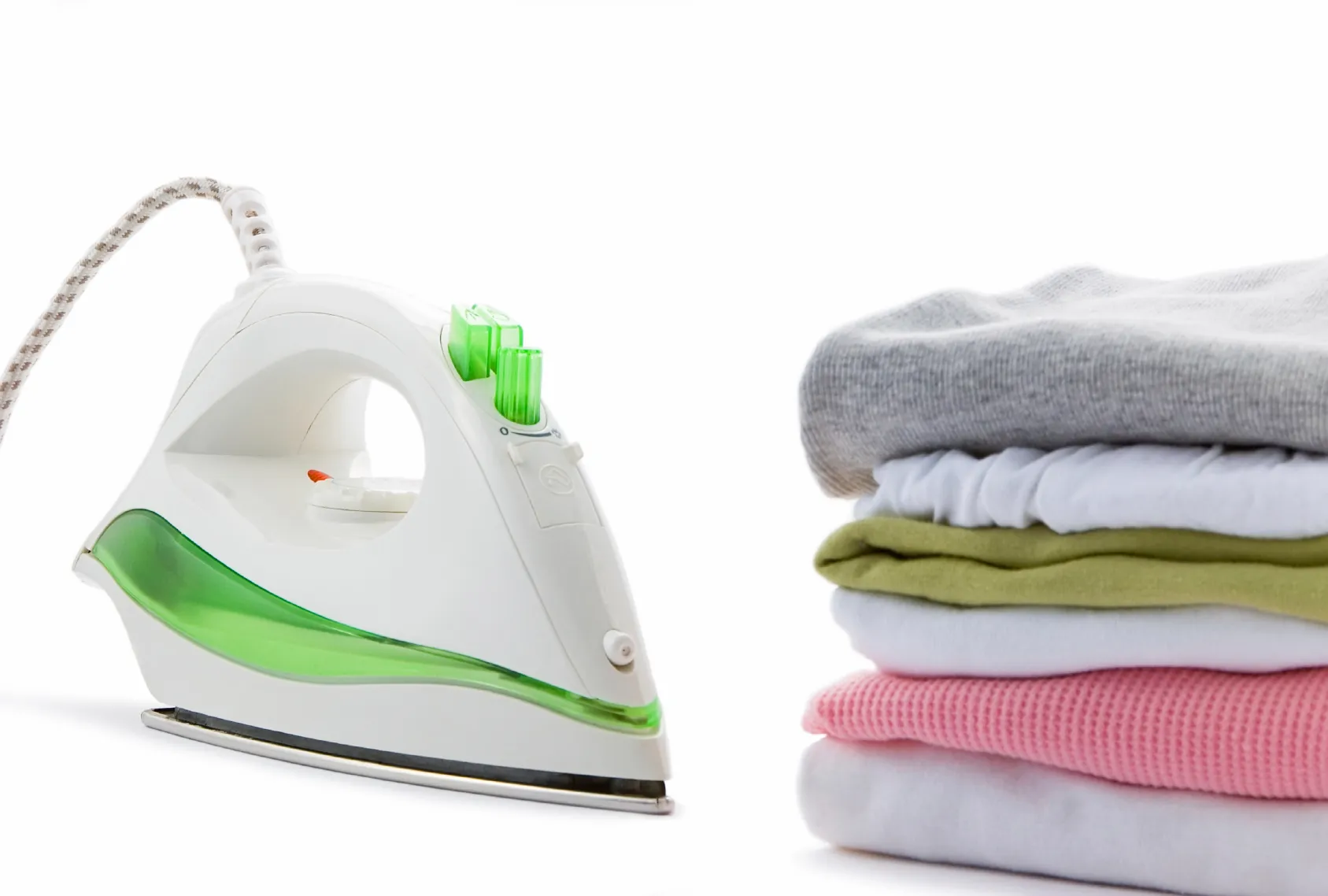 A steam iron beside a neat stack of freshly pressed clothes