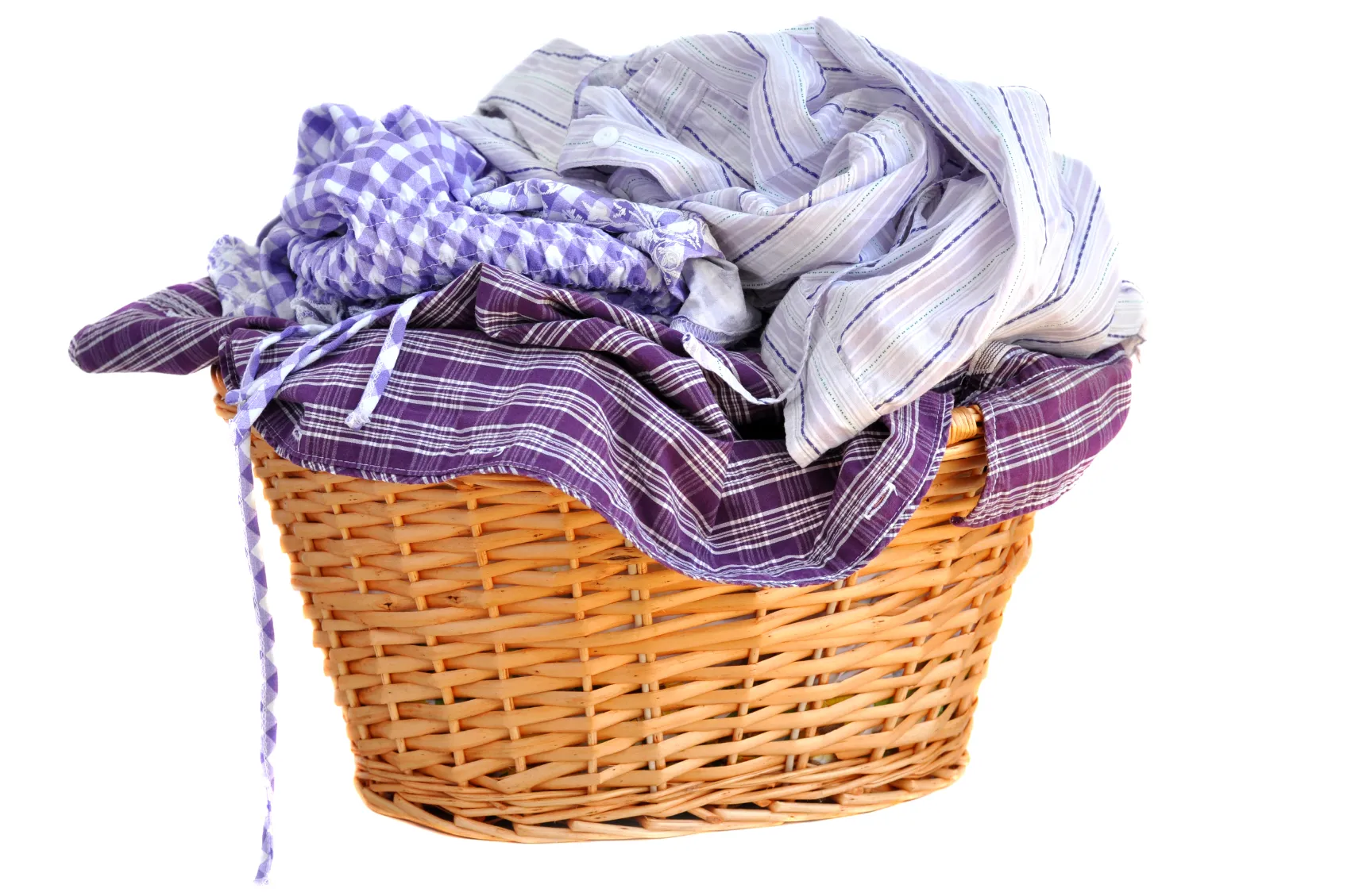 A wicker laundry basket filled with checked and striped bed linen